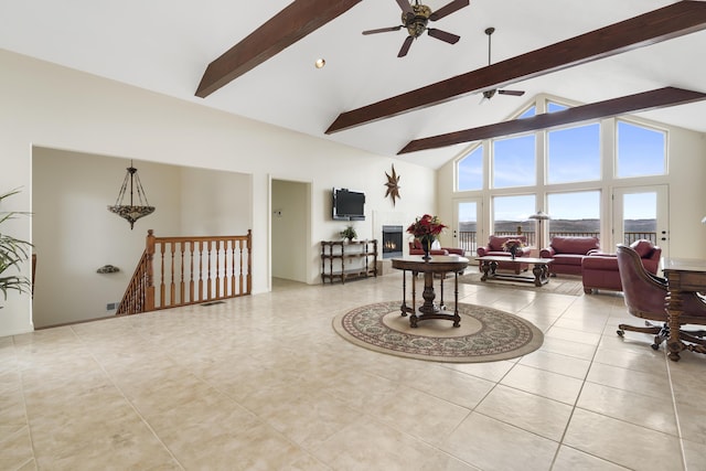 interior space with ceiling fan, high vaulted ceiling, an upstairs landing, a lit fireplace, and beam ceiling