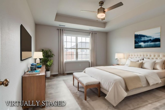 bedroom with a tray ceiling, a ceiling fan, visible vents, and baseboards