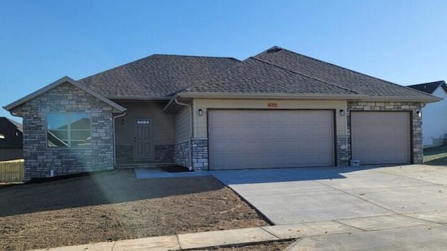 ranch-style house featuring driveway, a shingled roof, an attached garage, and stone siding