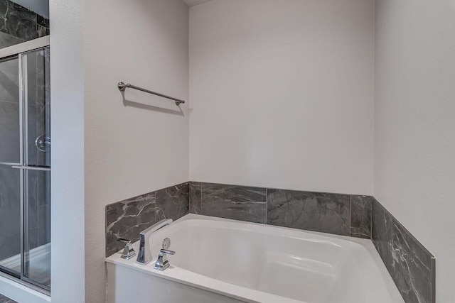 bathroom featuring a shower stall and a bath