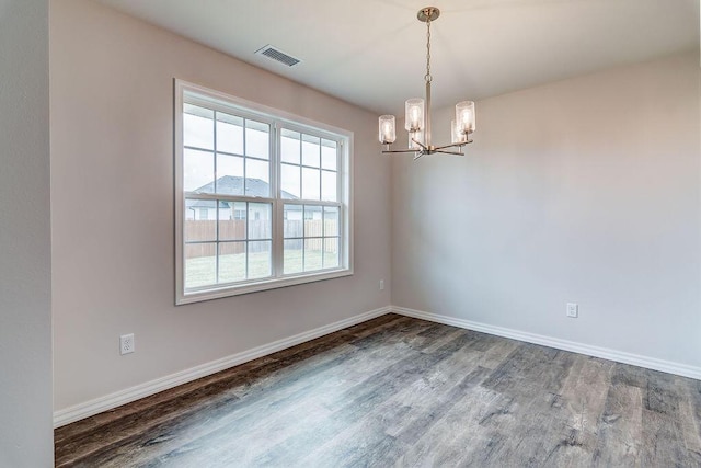 empty room featuring an inviting chandelier, baseboards, visible vents, and wood finished floors