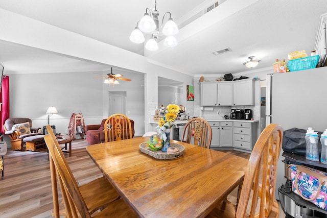 dining area with light wood-type flooring, visible vents, and crown molding