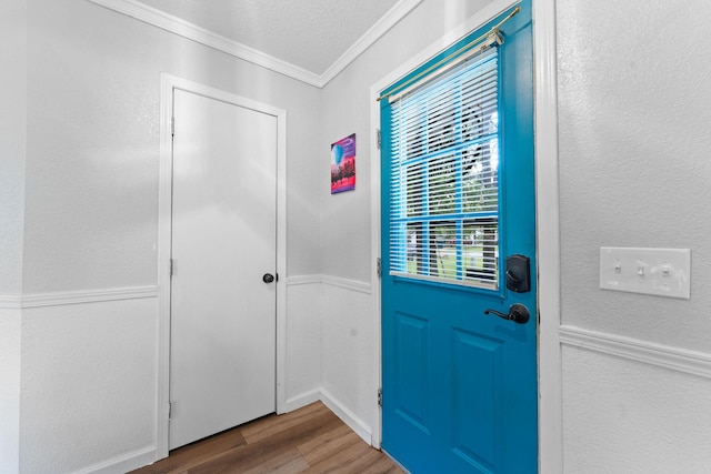 entryway featuring ornamental molding, a textured wall, a textured ceiling, and wood finished floors