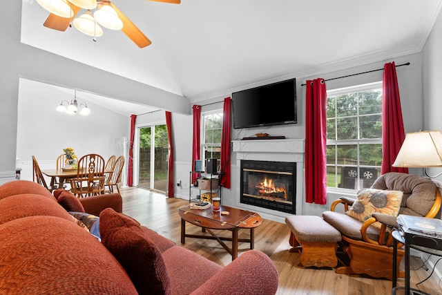 living room featuring vaulted ceiling, a large fireplace, wood finished floors, and a healthy amount of sunlight