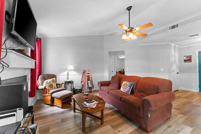 living area featuring light wood finished floors, a fireplace, and ornamental molding