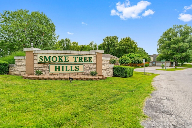 community / neighborhood sign with aphalt driveway and a lawn