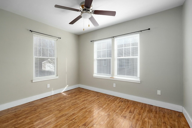 empty room with wood finished floors, a wealth of natural light, and baseboards