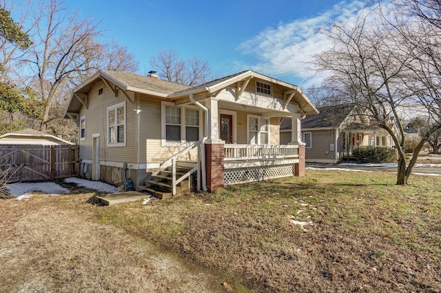 view of front of house featuring covered porch, a shingled roof, fence, a chimney, and a front yard