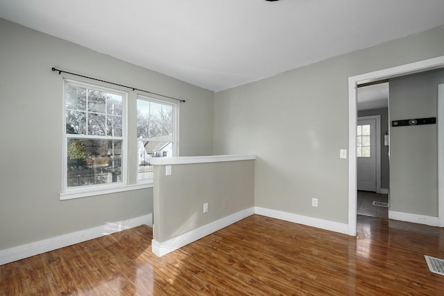 spare room with visible vents, baseboards, and wood finished floors