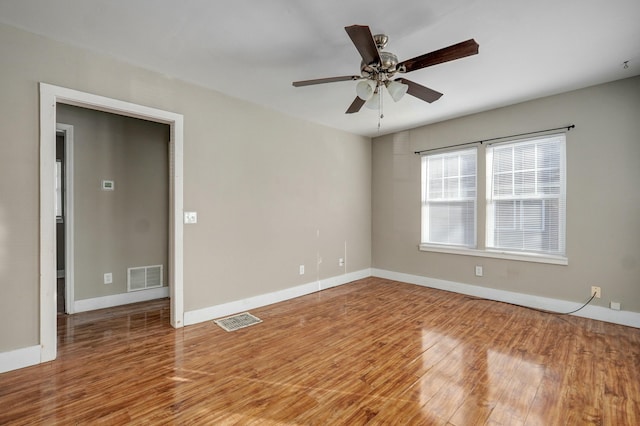 unfurnished room with baseboards, visible vents, ceiling fan, and wood finished floors