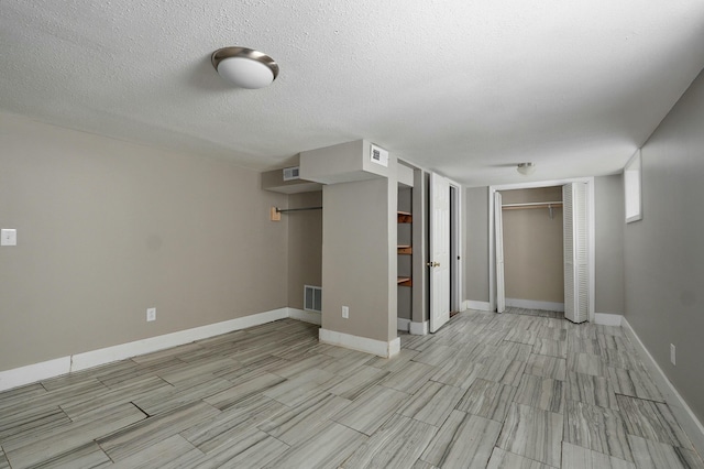 unfurnished room with baseboards, visible vents, and a textured ceiling