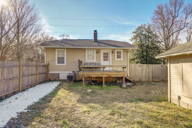 back of house with a yard, a chimney, a wooden deck, and fence