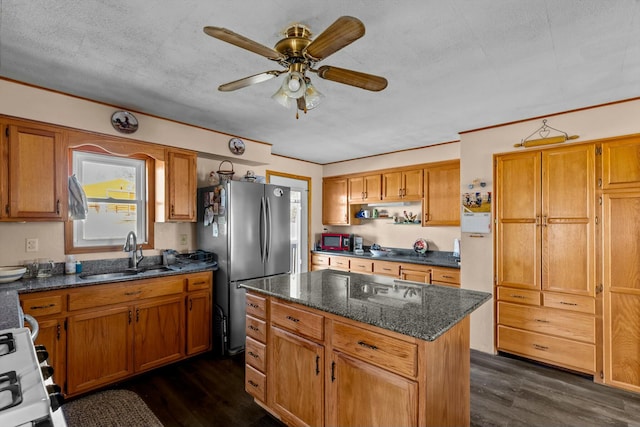 kitchen featuring dark wood finished floors, a kitchen island, a sink, and freestanding refrigerator