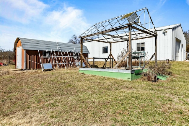 back of house with a pole building, an outbuilding, and a yard