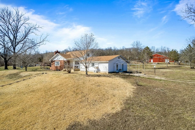 view of front of home with a rural view, driveway, and a chimney