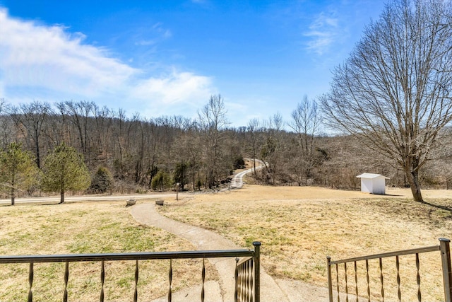 view of yard with a shed, an outdoor structure, and a wooded view