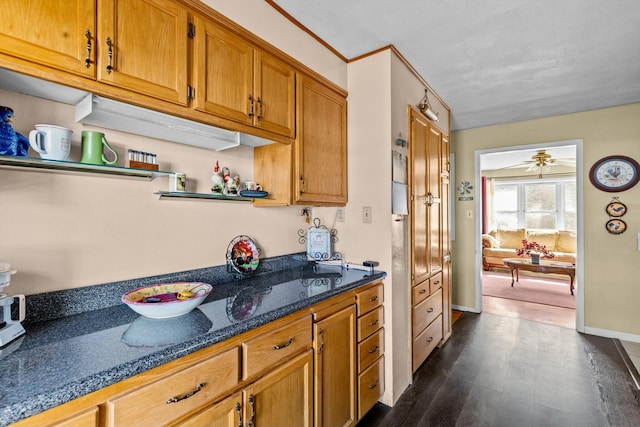 kitchen featuring open shelves, dark wood-type flooring, brown cabinetry, dark stone counters, and baseboards