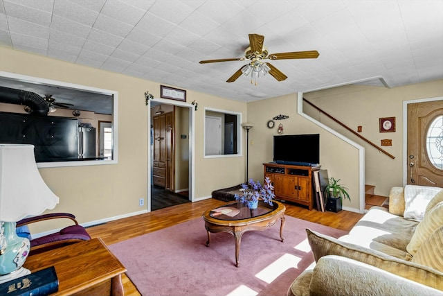 living room with stairway, ceiling fan, baseboards, and wood finished floors