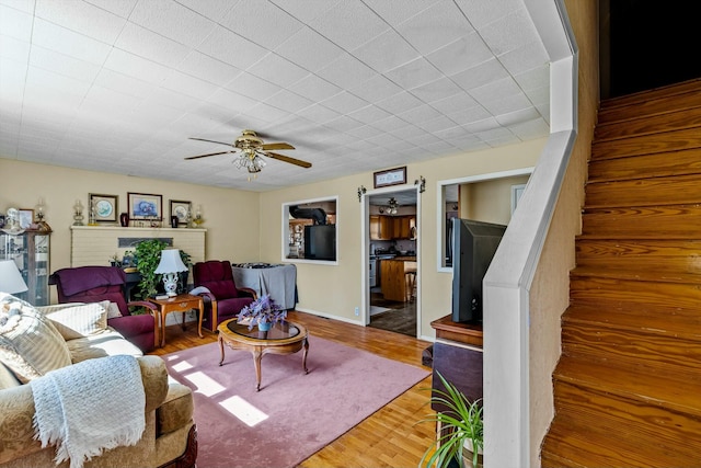 living area with ceiling fan, stairway, and wood finished floors