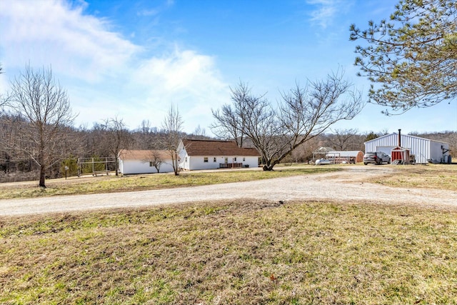 view of yard with dirt driveway, an outbuilding, and a detached garage