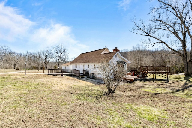 view of side of property with a chimney, a lawn, and a wooden deck