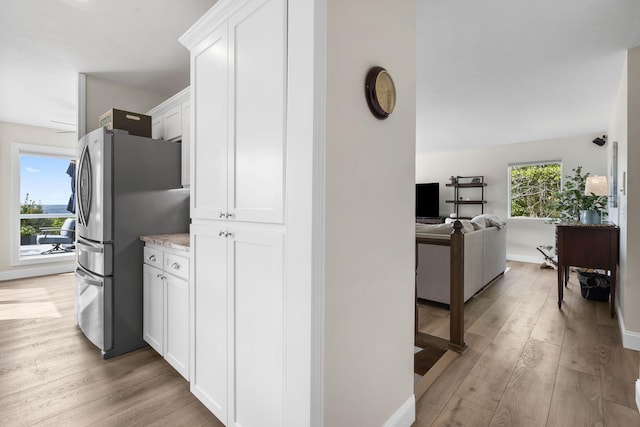 kitchen with light wood-style flooring, open floor plan, white cabinets, and freestanding refrigerator