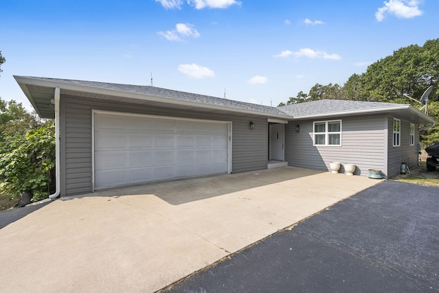 single story home featuring driveway, an attached garage, and roof with shingles