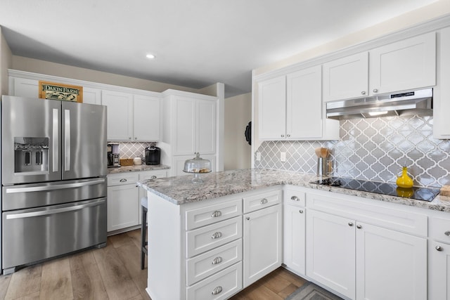 kitchen featuring black electric stovetop, stainless steel fridge, white cabinets, and under cabinet range hood