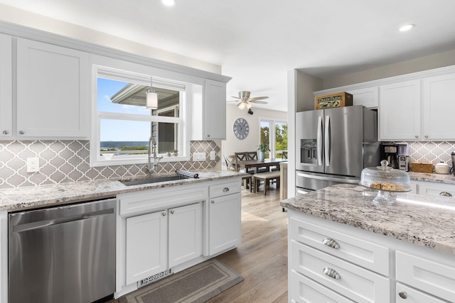 kitchen with tasteful backsplash, stainless steel appliances, light wood-style floors, white cabinetry, and a sink