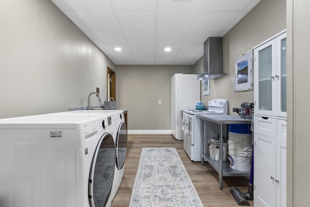 clothes washing area featuring laundry area, baseboards, light wood-style flooring, separate washer and dryer, and recessed lighting