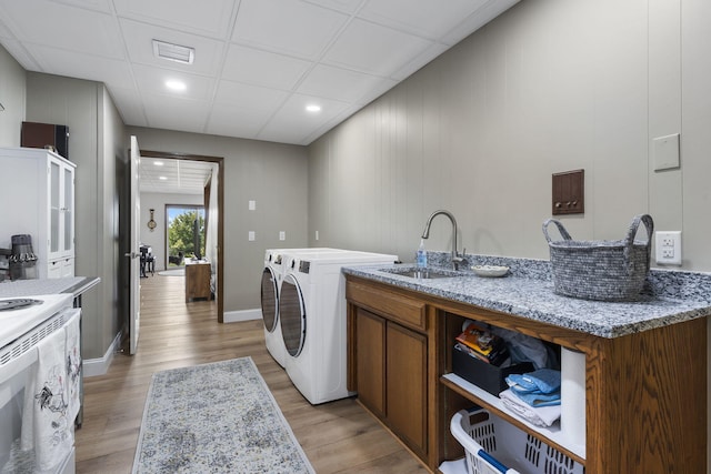 clothes washing area featuring light wood-style floors, visible vents, laundry area, and a sink