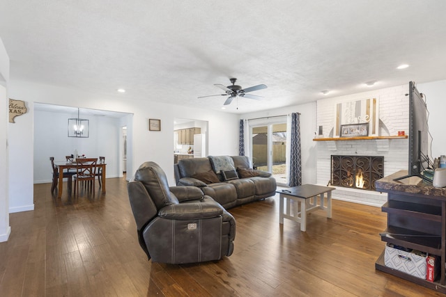 living room featuring baseboards, dark wood-style floors, ceiling fan, a textured ceiling, and a fireplace