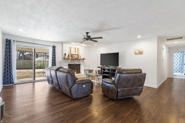 living area with a textured ceiling, hardwood / wood-style floors, a fireplace, and visible vents