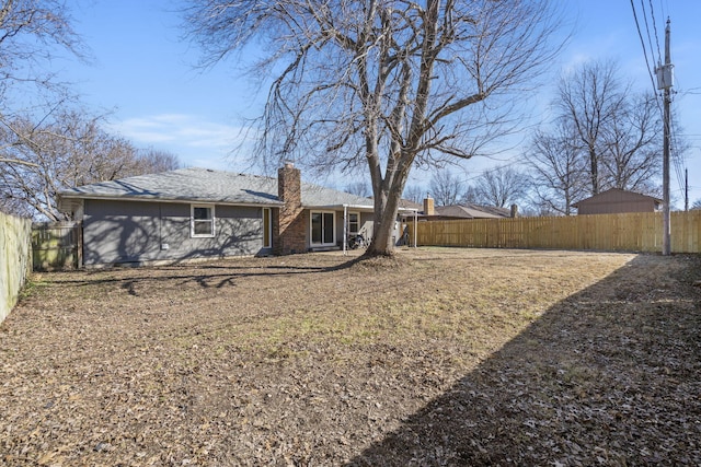 rear view of property with a fenced backyard and a chimney