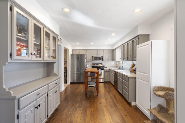 kitchen with dark wood finished floors, stainless steel appliances, light countertops, gray cabinetry, and a sink