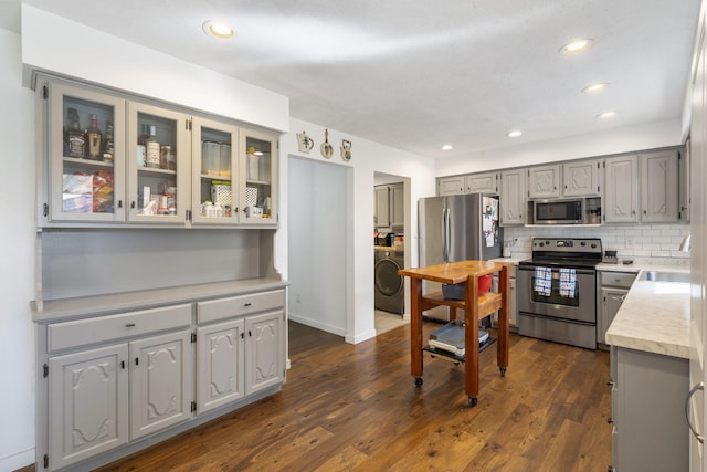 kitchen with stainless steel appliances, washer / dryer, light countertops, and gray cabinetry