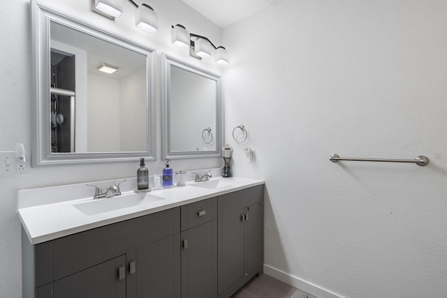 bathroom featuring double vanity, tile patterned floors, a sink, and baseboards