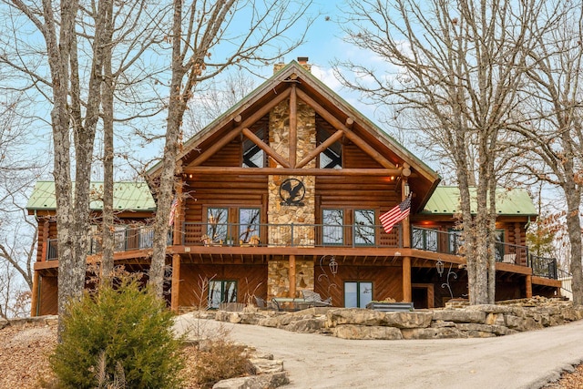 rear view of property with stone siding, a chimney, metal roof, and log exterior