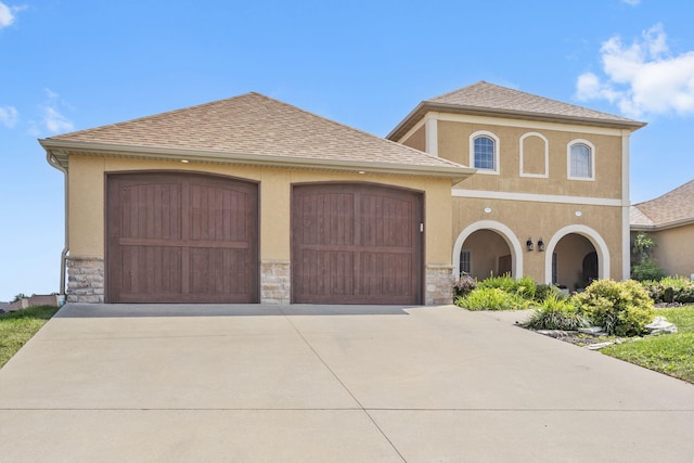 view of front of property featuring roof with shingles, driveway, and stucco siding