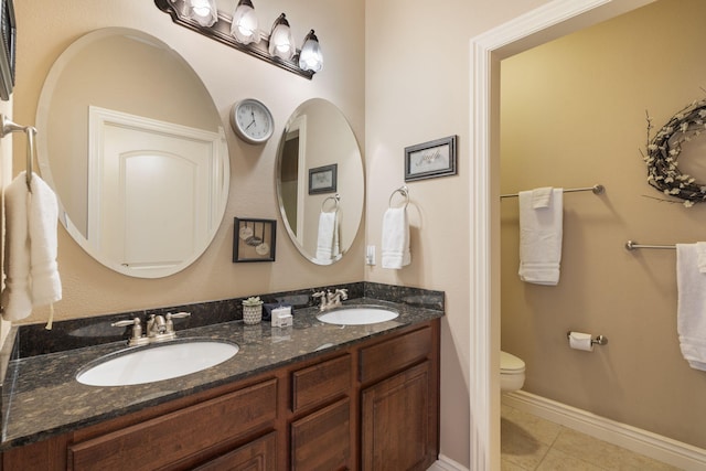 bathroom with double vanity, a sink, toilet, and tile patterned floors