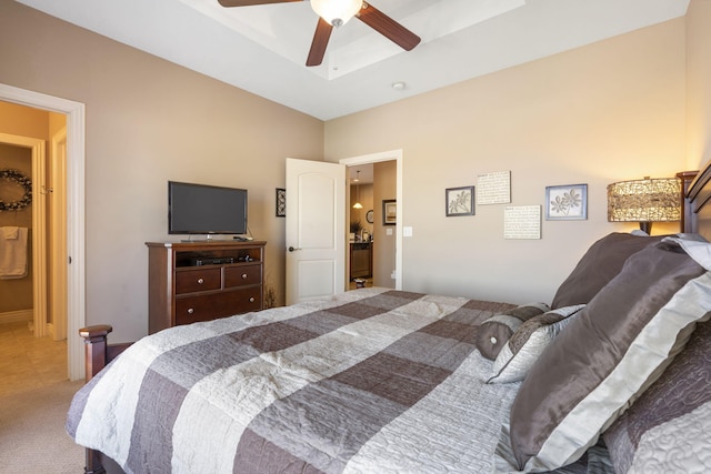 carpeted bedroom featuring a raised ceiling and a ceiling fan