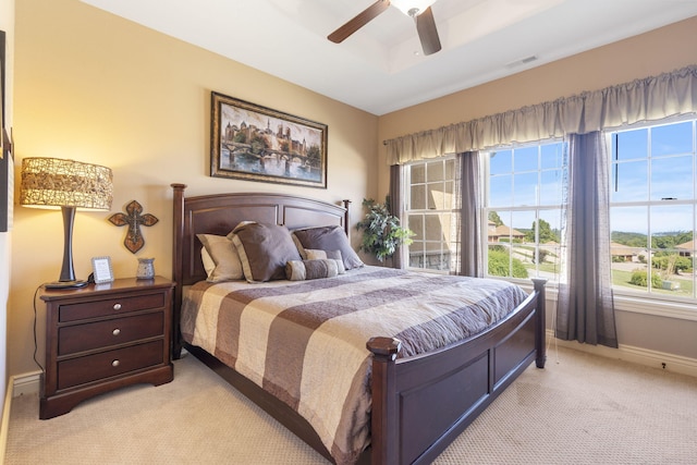 bedroom with light carpet, visible vents, baseboards, a ceiling fan, and a raised ceiling