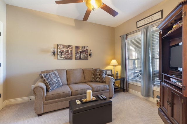 living area with baseboards, a ceiling fan, and light colored carpet