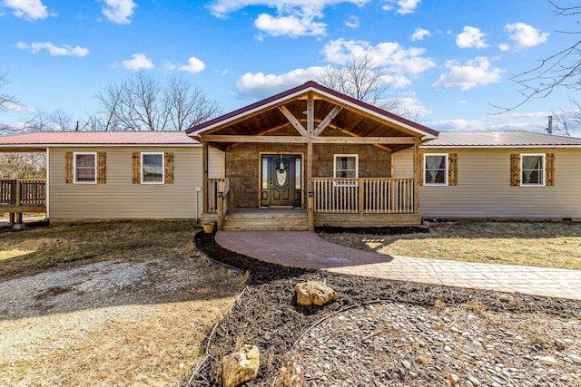 ranch-style house featuring covered porch and metal roof