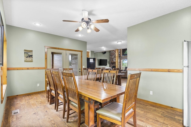 dining room with french doors, light wood finished floors, visible vents, a ceiling fan, and baseboards