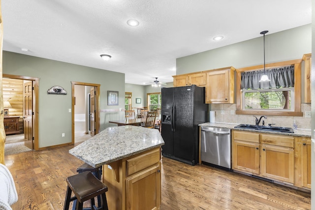 kitchen featuring dishwasher, a sink, plenty of natural light, and black fridge with ice dispenser