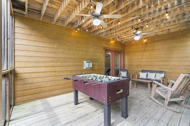 playroom with ceiling fan, wood walls, and wood finished floors