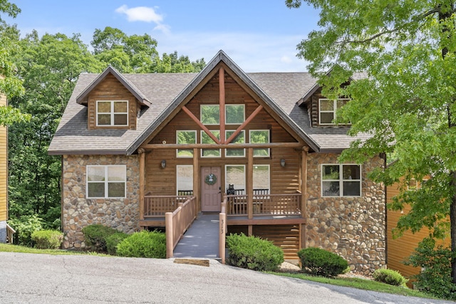 view of front of home featuring a porch, stone siding, and a shingled roof