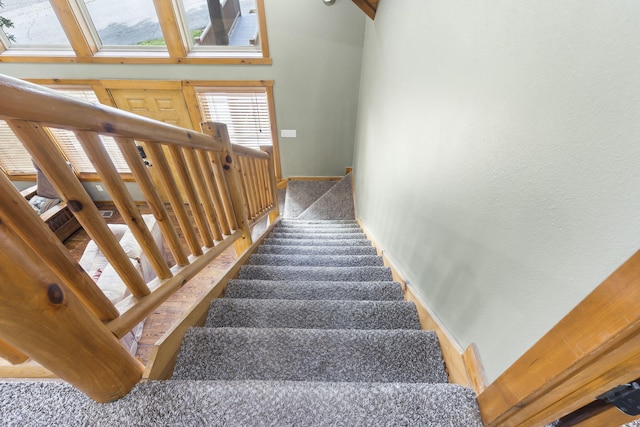 staircase with carpet floors, a towering ceiling, and baseboards