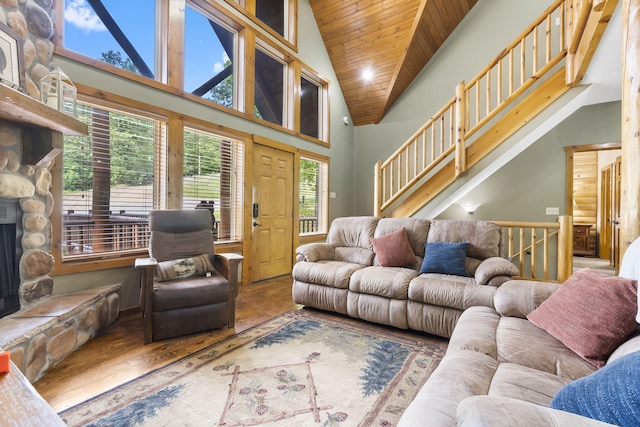 living room featuring high vaulted ceiling, a fireplace, wood finished floors, wood ceiling, and stairs